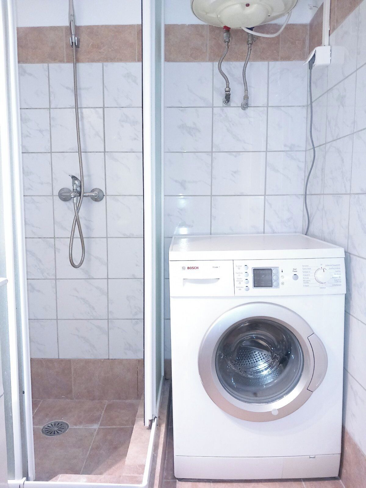 A compact bathroom with a shower, a Bosch washing machine, and a wall-mounted sink.