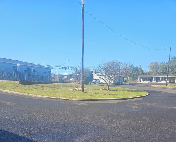 A parking lot with a building on the left, a small tree in the center, and a motel on the right.