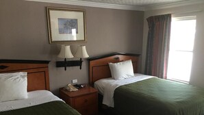Ein Hotelzimmer mit zwei Betten, einem Nachttisch mit Telefon, einem gerahmten Bild an der Wand und einem Fenster mit Vorhängen.