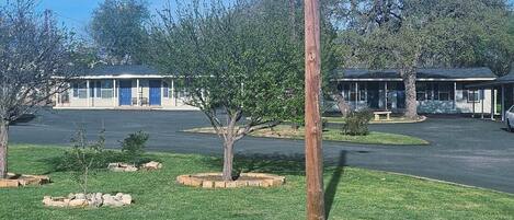 A building with a blue door, surrounded by a parking lot and a grassy area with trees.