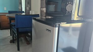 Eine kompakte Küche mit Kühlschrank, Mikrowelle und einem Essbereich mit Stuhl und Tisch.