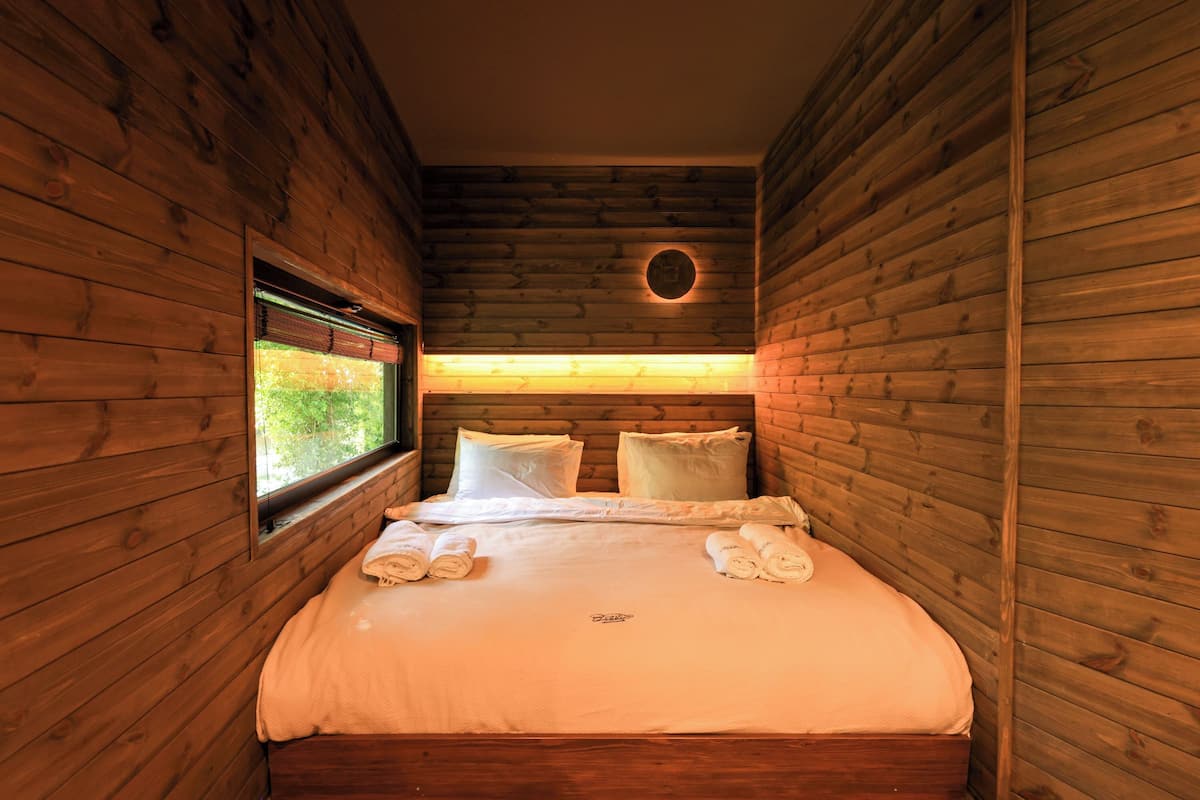 Une chambre à coucher de style cabane en bois, avec un lit, des oreillers et une fenêtre.