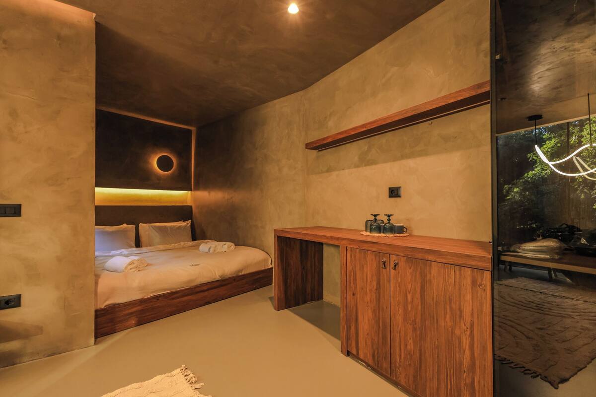 Une chambre à coucher moderne avec un lit en bois, un banc intégré et une lucarne circulaire.