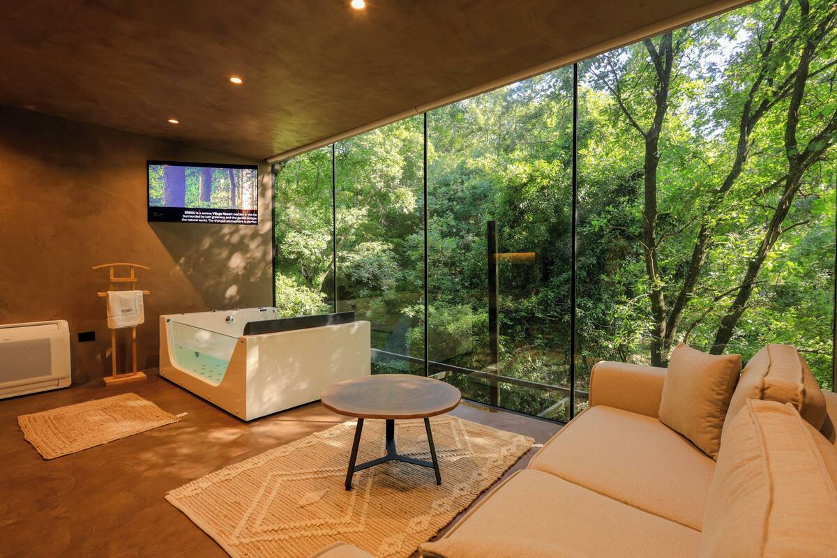 Une pièce moderne dotée d’une grande fenêtre, d’une table de massage et d’un canapé.