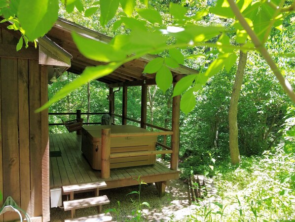 A wooden cabin with a bench and a table, surrounded by lush greenery. - Old Man's Haven - Cabin 4 (Logan)