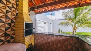 An outdoor kitchen area with a brick wall and a metal countertop.