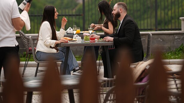 Un espace repas avec des tables dressées pour le repas, offrant une vue sur un paysage montagneux.