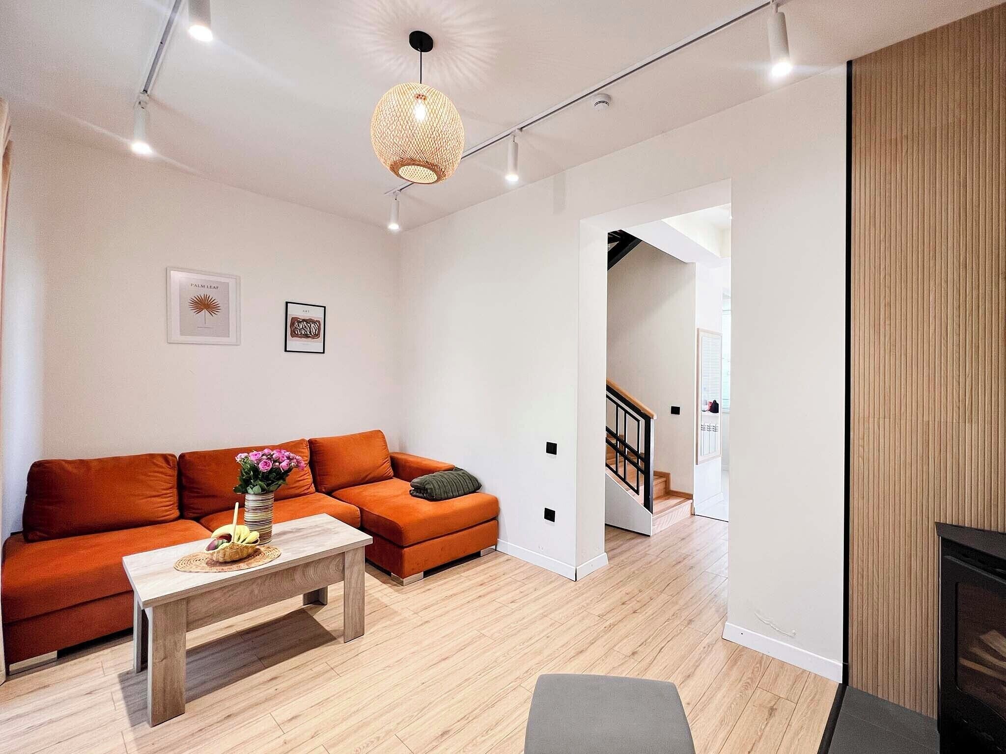 A modern living room with a sofa, a coffee table, and a hanging light fixture.