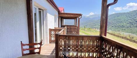 A wooden deck with a table and chairs, overlooking a mountainous landscape.