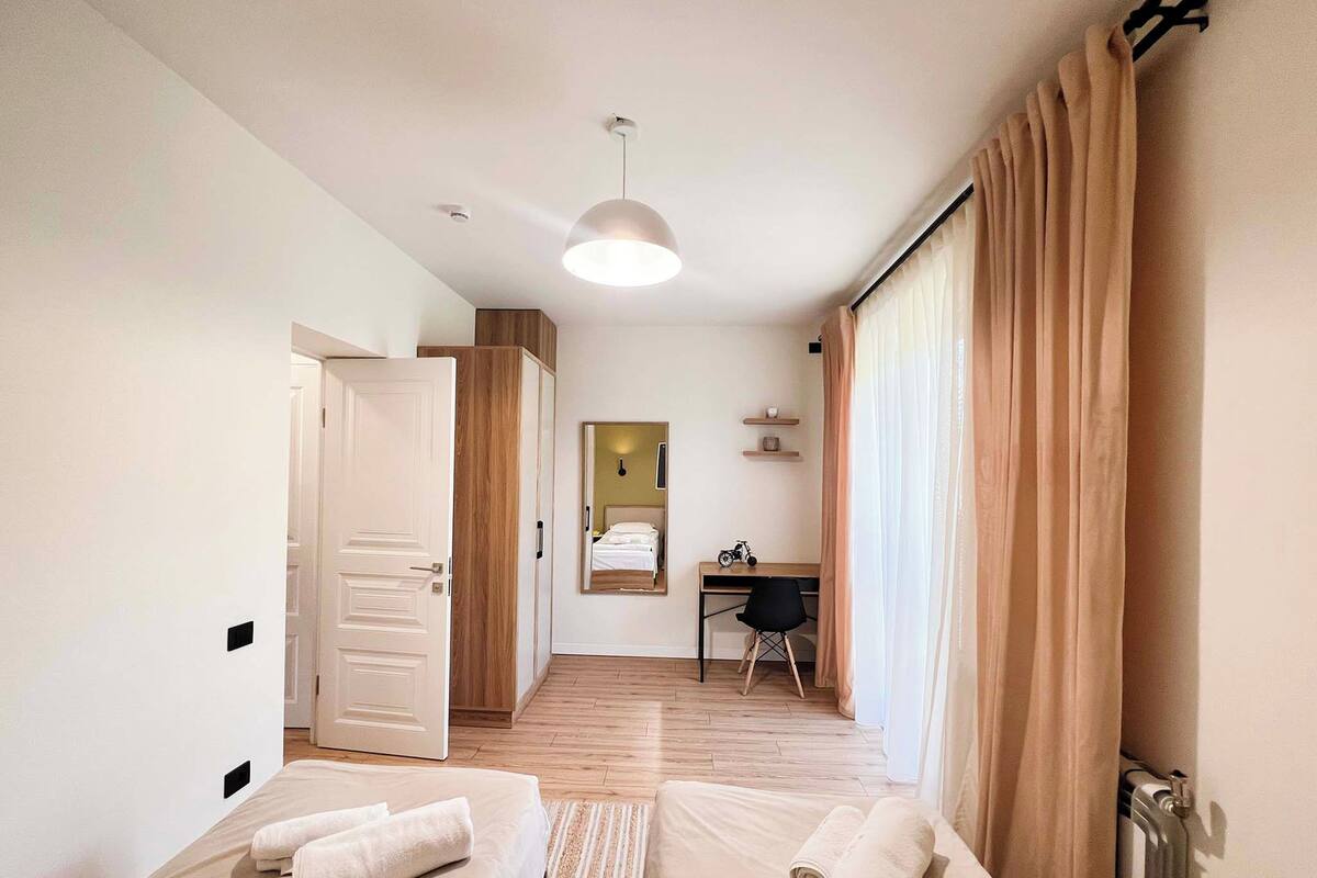 Una habitación de hotel con cama, escritorio, silla, espejo y radiador.