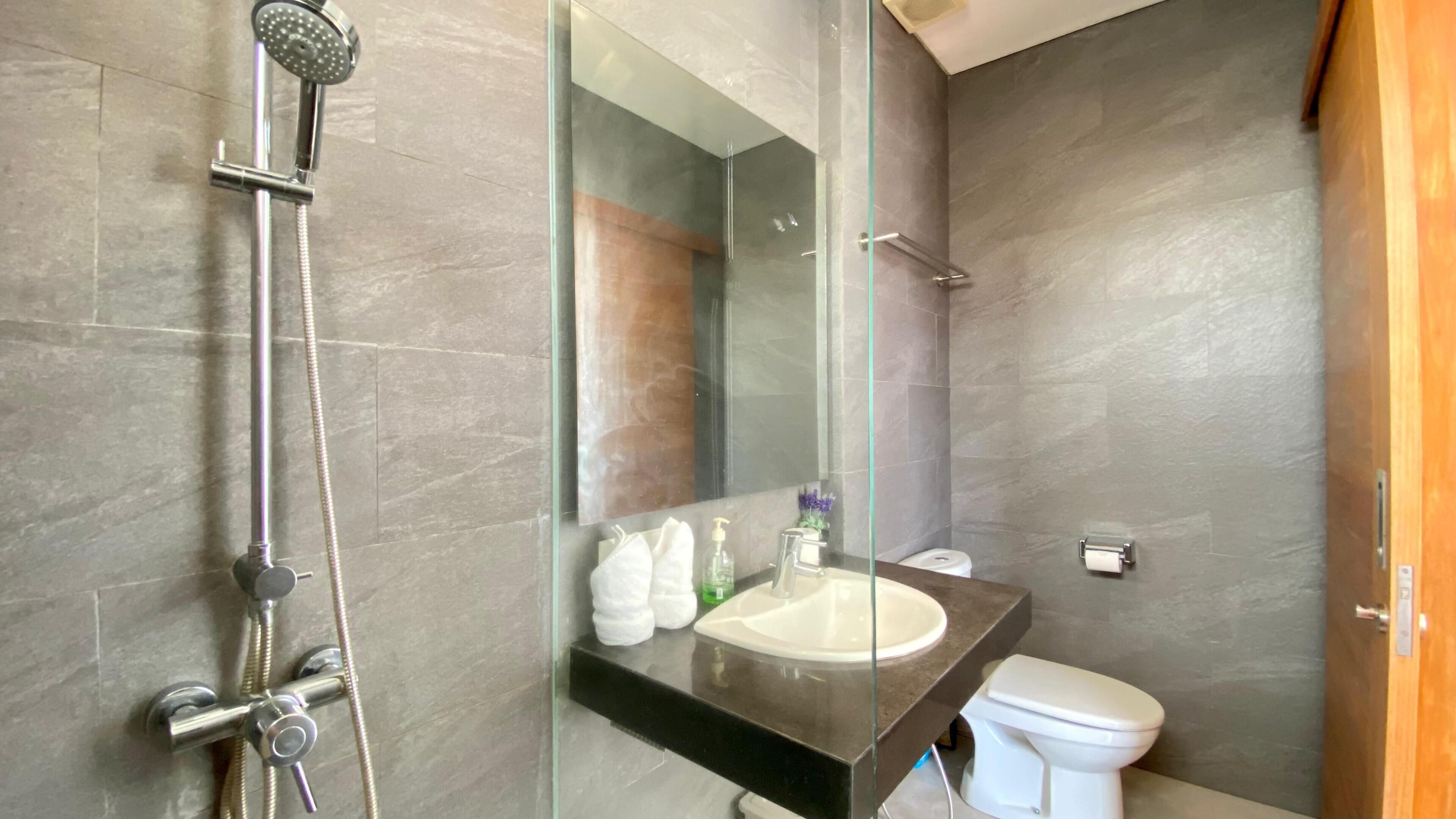 A modern bathroom with a glass-enclosed shower, a sink, and a toilet.