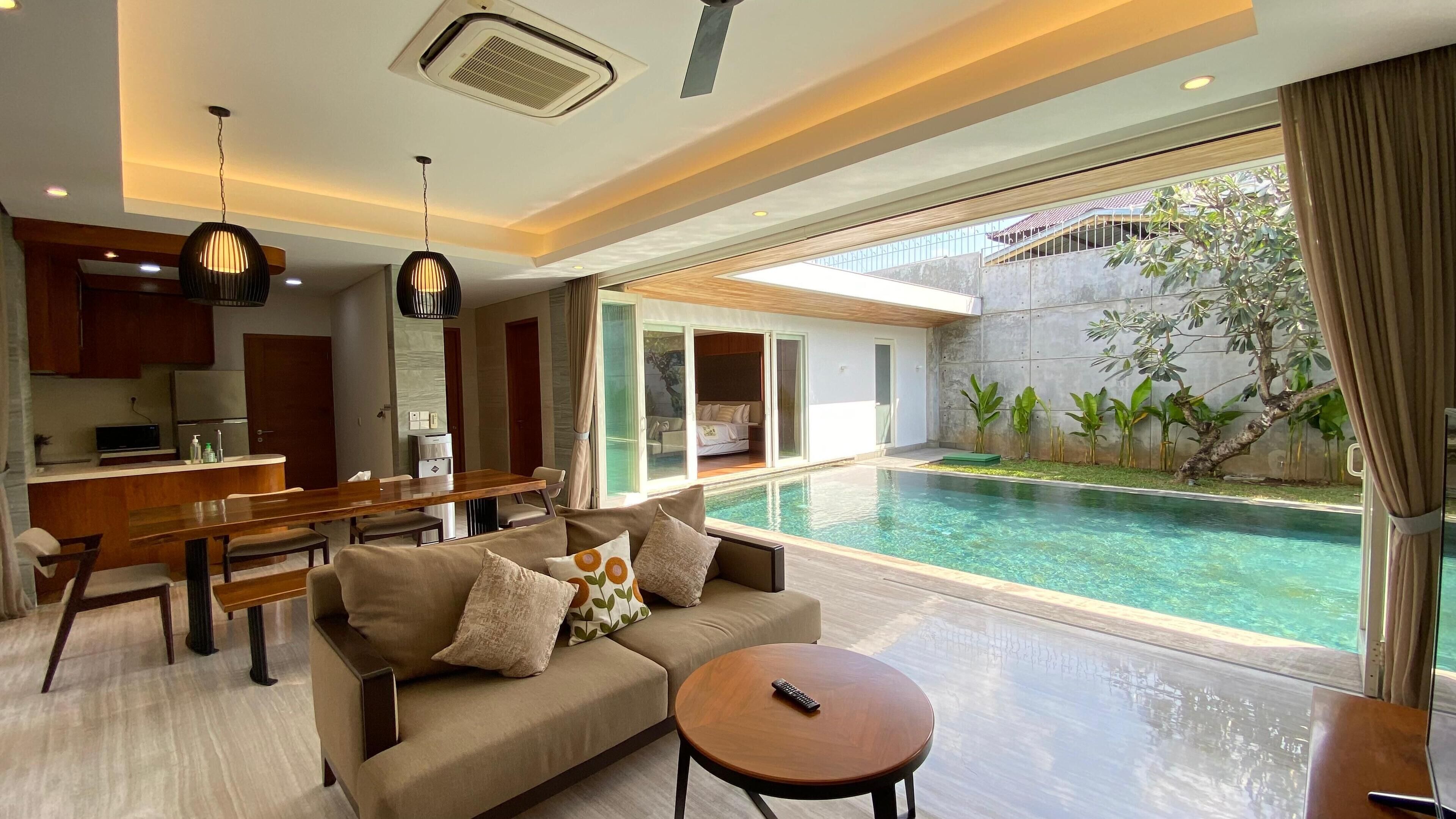 Ein modernes Wohnzimmer mit Pool, Essbereich und Küche.