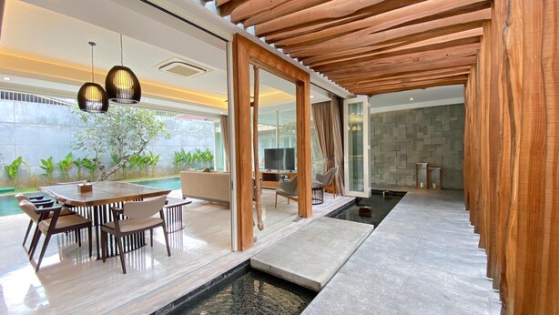 Una sala de estar moderna con piscina, techo de madera y un comedor con mesa y sillas.