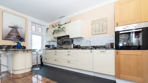 A modern kitchen with white cabinetry, a black countertop, and a stainless steel oven. - Seaview Retreat - Breathtaking coastal views, 2 bedroom apartment (South Shields)
