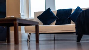 A modern living room with a beige sofa, two dark blue cushions, and a wooden coffee table. - Seaview Retreat - Breathtaking coastal views, 2 bedroom apartment (South Shields)