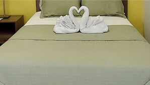 Un lit recouvert d’une couverture verte et orné de deux serviettes blanches disposées en forme de cygnes.
