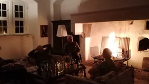 A dimly lit room with a fireplace, wooden beams, and a table with glasses and bottles. - Apartment in medieval castle from the 14th century on the Weser cycle path (Petershagen)