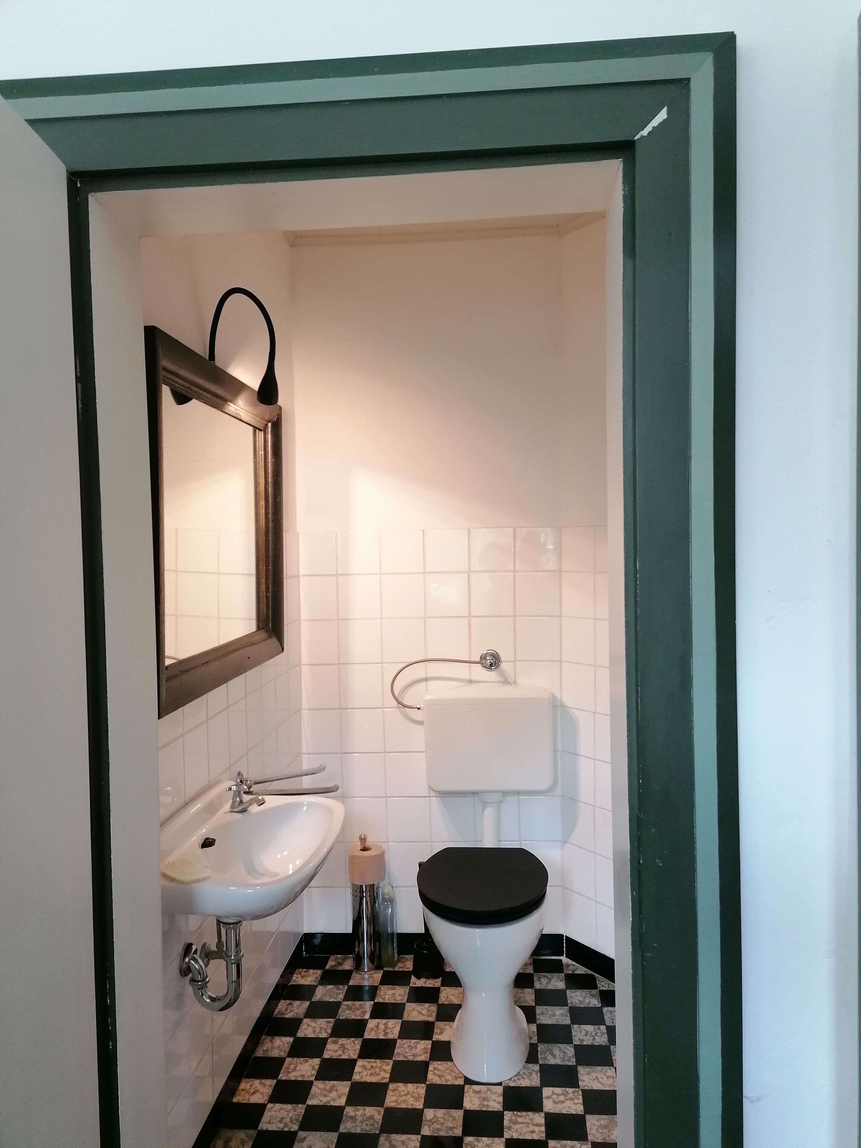 Un bagno con lavandino, WC e specchio.