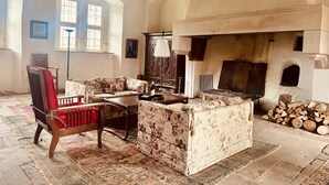 A traditional living room with a fireplace, wooden furniture, and a patterned rug. - Apartment in medieval castle from the 14th century on the Weser cycle path (Petershagen)