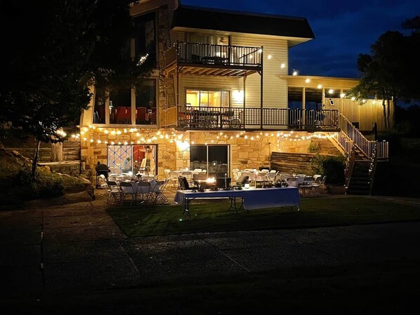 A two-story building with a balcony, outdoor seating area, and string lights.