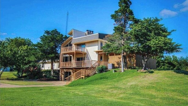 Une maison à deux étages avec un balcon, une véranda et un grand jardin.