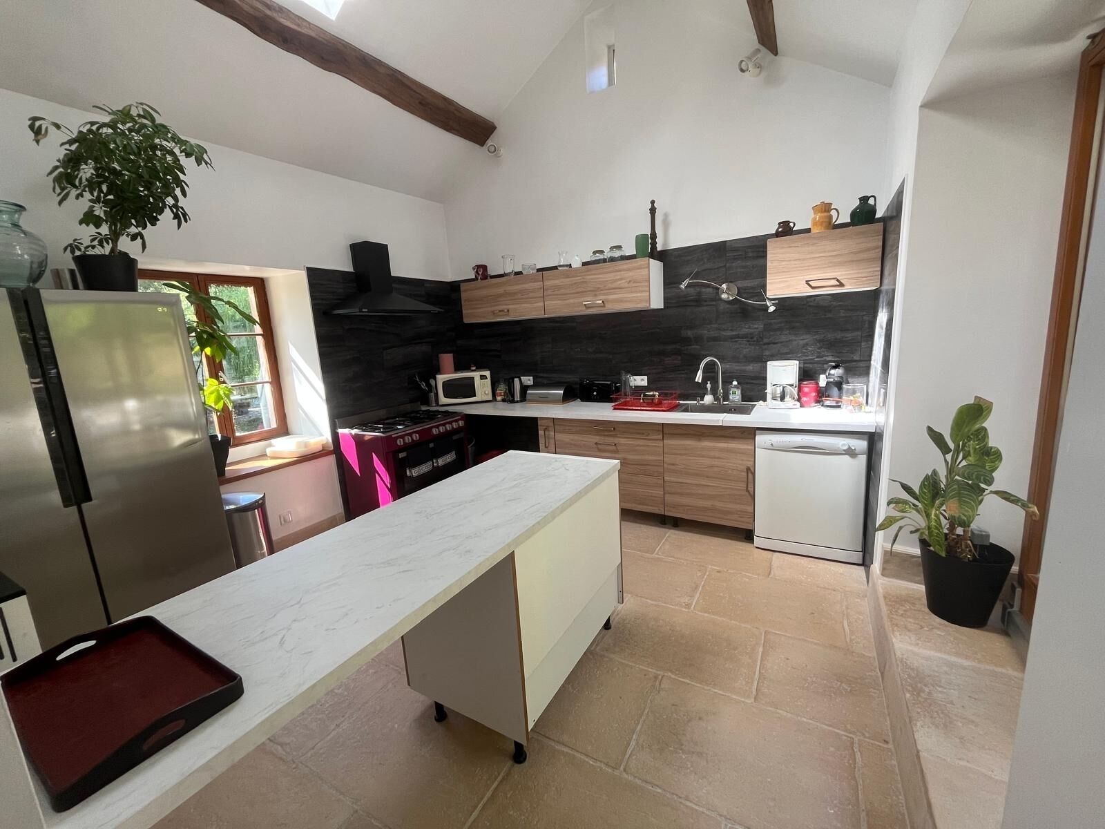 Une cuisine moderne dotée d’un plan de travail en marbre, de meubles en bois, d’un four encastré et d’un lave-vaisselle.