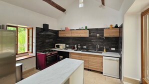 Une cuisine moderne dotée d’un grand îlot central, d’appareils électroménagers intégrés et offrant une vue par une fenêtre.