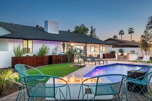 A modern house with a swimming pool, outdoor seating, and a fire feature.