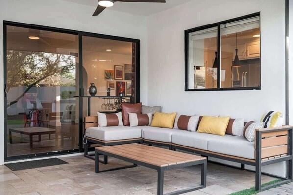 A modern living room with a sectional sofa, a wooden coffee table, and a glass door leading to a patio area.