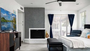 A modern bedroom with a fireplace, a bed, a desk, and a television. - Turquoise Retreat - Pool, Putting Green, Location! (Scottsdale)