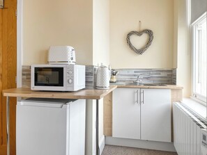 A compact kitchen with white appliances, a heart-shaped decoration on the wall, and a window providing natural light. - Denelea Studio 2 - UK49953 (Scarborough)