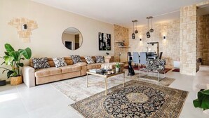 A living room with a sofa, coffee table, rugs, and a stone wall. - Welcome to your Seaside Home (Varazze)