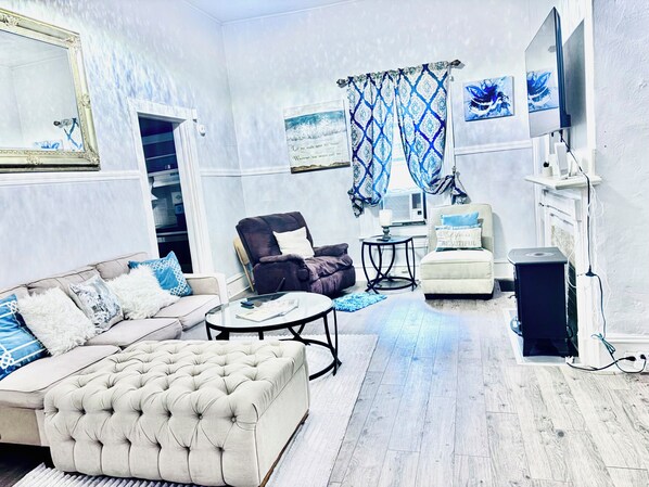 Ein Wohnzimmer mit Sofa, Sessel, Hocker und einem kleinen Tisch.