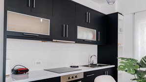 Una cucina moderna con mobili neri, un piano di lavoro bianco e un forno integrato.