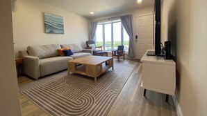 Una sala de estar moderna con sofá, mesa de centro y mueble para televisión.