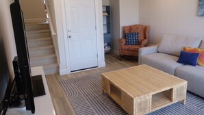 Una sala de estar con un sofá, una silla, una mesa de centro y una escalera.
