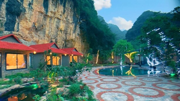 A hotel with a pool, stone pathway, and mountain backdrop.