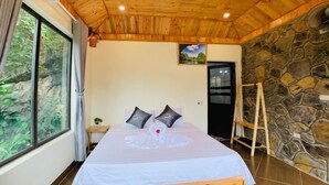 A wooden ceiling, a bed with pillows, a window, and a stone wall.