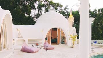 A white, dome-shaped building with a pool in the foreground.