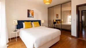 Ein Hotelzimmer mit einem großen Bett, einem Nachttisch mit Lampe, einem Spiegel und einem Bild an der Wand.