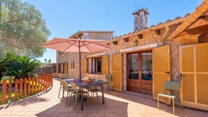 Une terrasse extérieure avec une table, des chaises et un grand parasol.