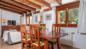 Un coin repas avec une table et des chaises en bois, un téléviseur et un lit avec une couverture.