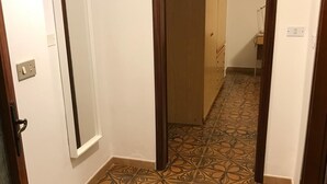A hallway with patterned flooring and wooden doors.