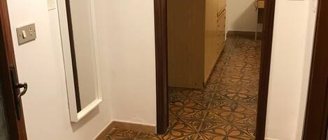 A hallway with patterned flooring and wooden doors.