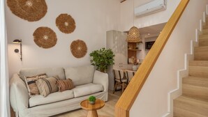 A living room with a sofa, a coffee table, and a staircase. - Marconia Boutique Residence   Dúplex Premium (Girona)