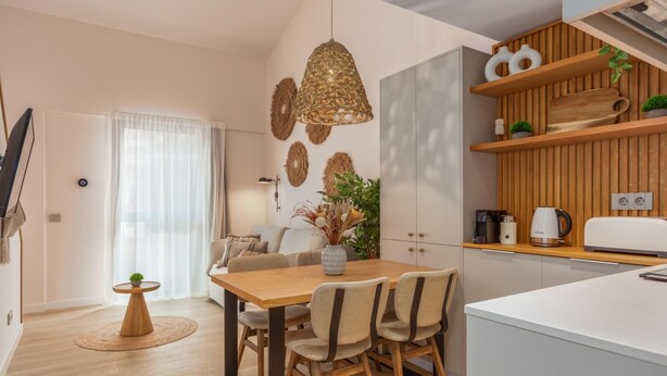 A modern kitchen with wooden cabinets, a dining table with chairs, and a hanging light fixture. - Marconia Boutique Residence   Dúplex Premium (Girona)