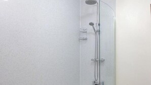 A modern bathroom with a freestanding bathtub, a glass-enclosed shower, and a plain white wall. - Clover Cottage (Saint Wenn)