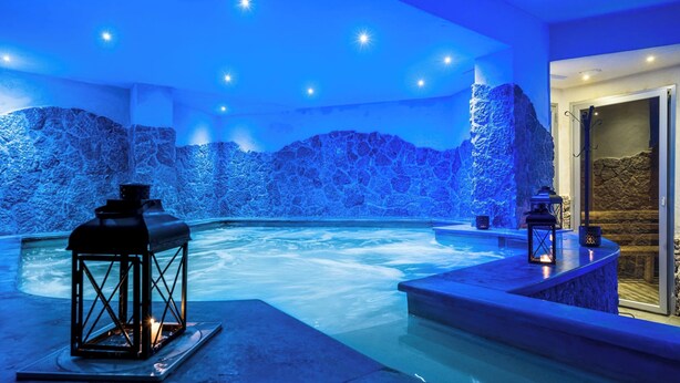 A spa area with a hot tub, stone walls, and lanterns. - TPH Rooms (Taormina)