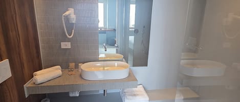 Een moderne badkamer met twee wastafels, een toilet en een douche.