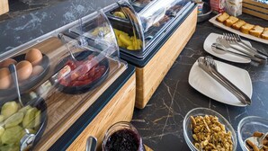 A buffet setup with various food items and a decorative vase. - TPH Rooms (Taormina)